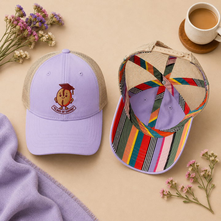 Two baseball caps on a beige surface with flowers and a cup of coffee.