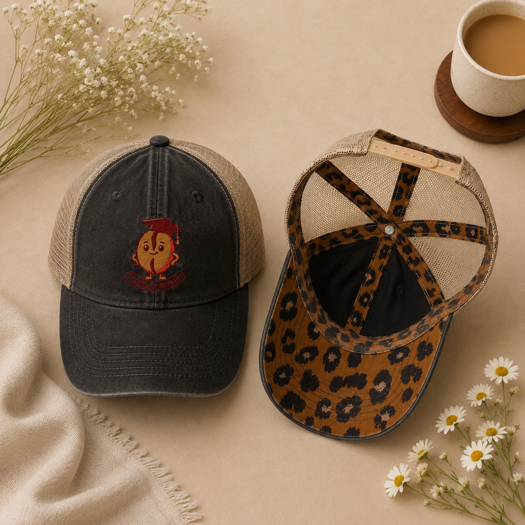 Two baseball caps on a beige surface with flowers and a cup of coffee.