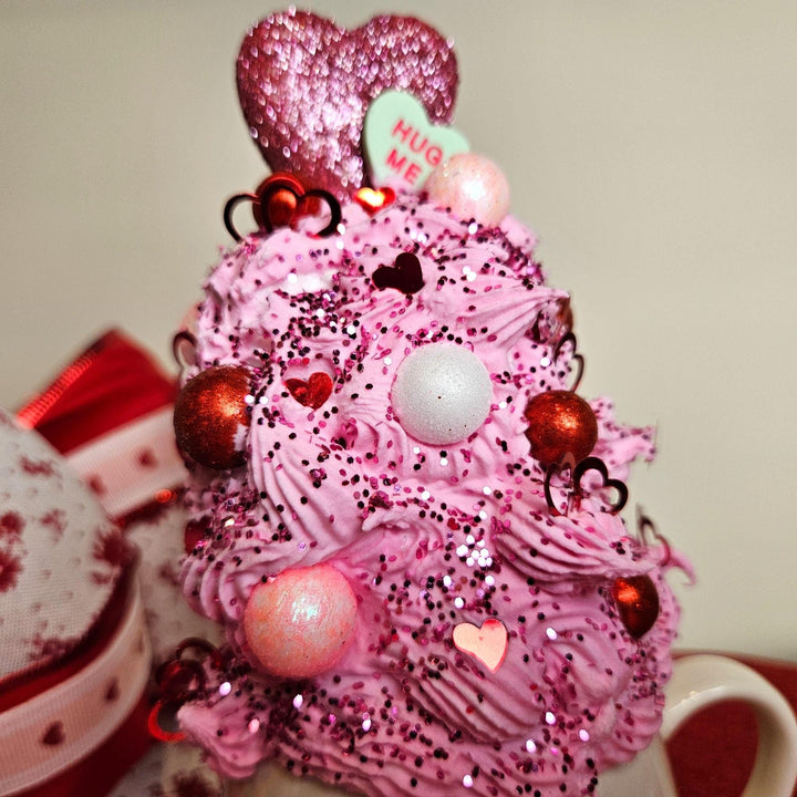 Pink decorative tree with heart and ball ornaments on a neutral background