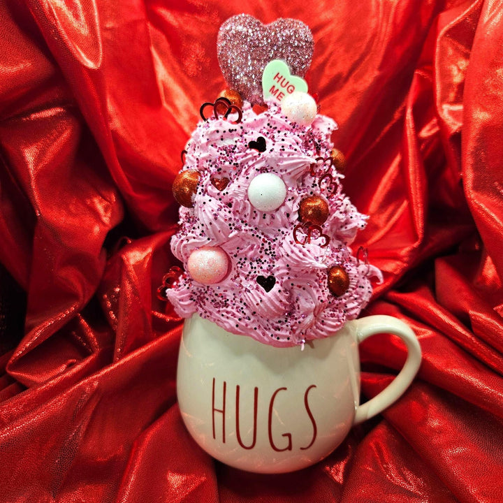 Decorative mug with pink whipped cream, heart-shaped objects, and &