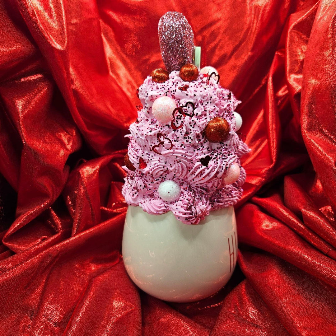 Decorative item with pink whipped cream and red candies on a red fabric background