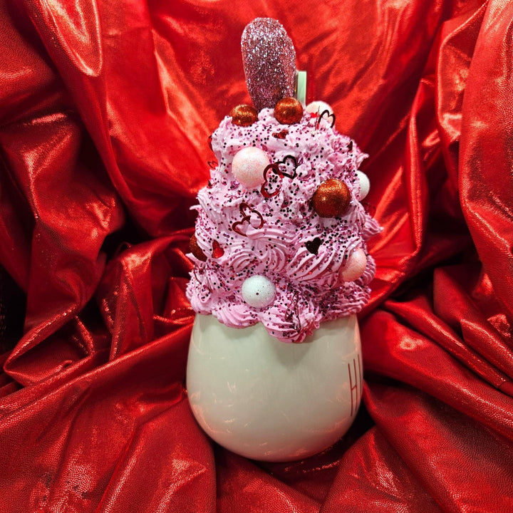 Decorative item with pink whipped cream and red candies on a red fabric background