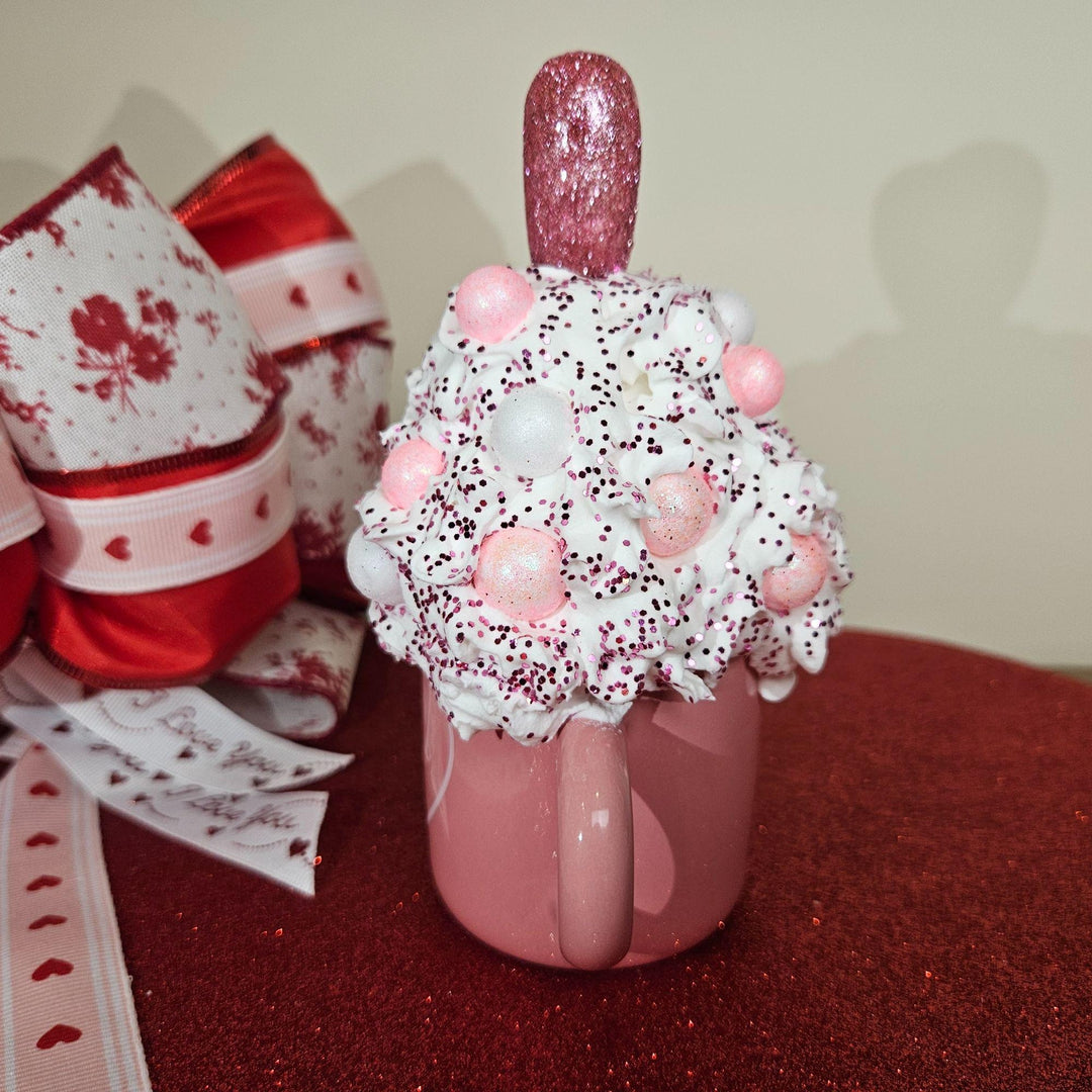 Decorative pink mug with a floral arrangement on a red surface